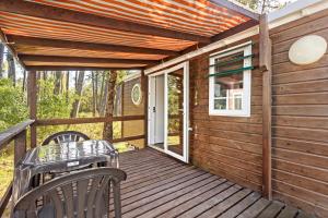 una terraza de madera con mesa y sillas en Bungalow T3 I V- 15 Min From Nazaré, en Pataias