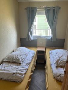 zwei Betten in einem kleinen Zimmer mit Fenster in der Unterkunft Spacious 10 birth Caravan Golden palm resort chapel st leonards Skegness in Chapel Saint Leonards