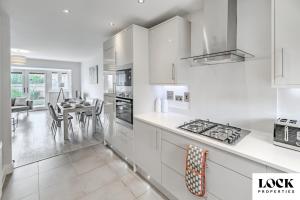 a kitchen with white cabinets and a dining room at Family & Contractor Friendly 3 bed house Sleeps 8 in Maidenhead in Maidenhead