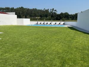 a lawn with chairs and a swimming pool at Lugar do Paraíso - duas casas, uma só experiência - Vila do Conde in Touguinho