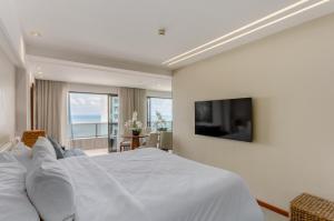 a bedroom with a white bed and a television at Urban - Beira Mar Boa Viagem in Recife
