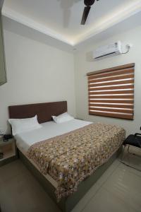 a bedroom with a bed and a window with a fan at Prem Sadan, Pandokhar Sarkar Dham in Indargarh