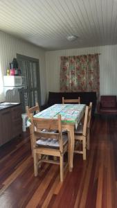 a table and chairs in a room with wooden floors at Chalé Paraíso Da Serra 01 in Gramado