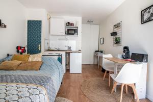 a bedroom with a bed and a table and a kitchen at Studio Les Cèdres, central et chaleureux ! in Cholet +10 photos