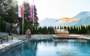 a swimming pool with a chair and an umbrella at Baumhaus by Hotel Gassner in Neukirchen am Großvenediger +35 photos