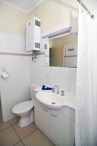 a white bathroom with a toilet and a sink at Coral Motel & Apartments in Port Vila