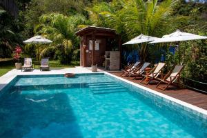 甘博阿Bella Gamboa Casa da Praia - Praia da Argila - Gamboa -的房子旁边有带椅子和遮阳伞的游泳池