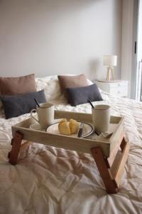 a tray with two cups and a plate on a bed at Urquiza Suite Premium Rental in Buenos Aires +28 photos