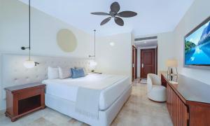 a white bedroom with a white bed and a tv at Grand Palladium Select White Sand Resort & Spa - All Inclusive in Akumal
