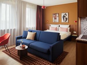 a hotel room with a bed and a blue couch at Numa Hamburg St Georg in Hamburg