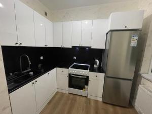 a kitchen with white cabinets and a stainless steel refrigerator at Sunrise Guesthouse UB in Ulaanbaatar
