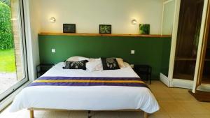 a bedroom with a large bed with a green wall at Domaine des Célestins - Loft Ginkgo in Bernay-en-Ponthieu