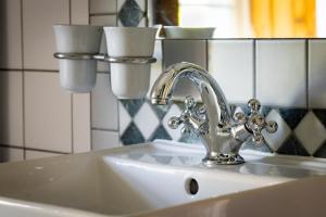 un lavandino del bagno con un rubinetto argentato e tazze di Haus Burgblick a Grimma