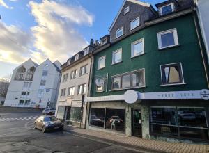 Un edificio verde con un coche aparcado delante. en Suite in Siegens Oberstadt, en Siegen