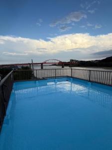a large blue swimming pool with a bridge in the background at ゲストハウスMOANa in Hitachinaka