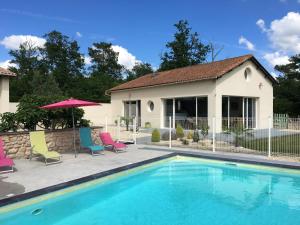 a swimming pool with chairs and a house at Loft piscine chauffée et couverte in Sauvignac
