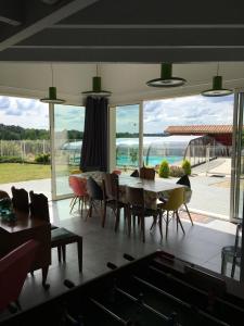 a dining room with tables and chairs and a large window at Loft piscine chauffée et couverte in Sauvignac