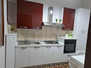 a kitchen with white cabinets and a sink and a stove at Il sorriso di Giuseppina in Bronte