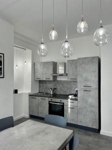 a kitchen with a table and several pendant lights at De Mio's Apartment in Murano