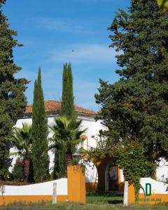 a white building with trees in front of it at Cortijo Negretti in Herrera de Alcántara