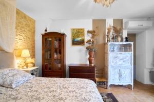 a bedroom with a bed and a dresser and a cabinet at Gite de La Fontaine de Laumede in Saint-Chamassy