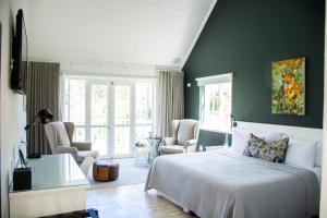 a bedroom with a bed and chairs in a room at Vida Nova Retreat in Hout Bay