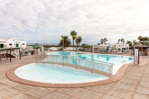 a swimming pool at a resort with palm trees and buildings at Bungalow Einstein Xej in San Bartolomé