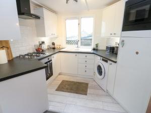 a kitchen with white cabinets and a washer and dryer at John's Folly in Sowerby Bridge
