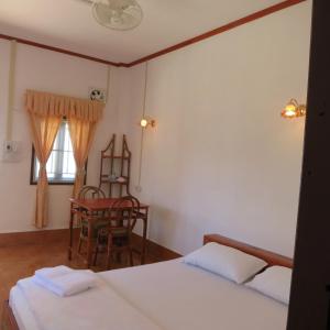 a bedroom with two beds and a chair and a window at Kongkeo Guesthouse in Muang Phônsavan