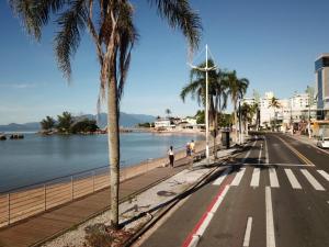 a street with palm trees next to a body of water at Residencial Morada Coqueiros in Florianópolis