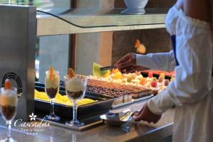 a person preparing a buffet of food with drinks at Cascadas Family Resort in Sunny Beach