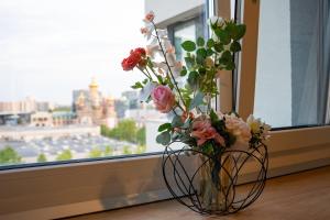 un vase rempli de fleurs assis sur un rebord de fenêtre dans l'établissement Sunset View Pipera 56 Blvd Ivory, à Bucarest