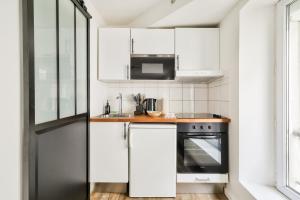 una pequeña cocina con armarios blancos y microondas en Studio moderne aux portes de Paris, en Montreuil