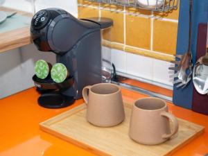 two cups on a cutting board with a coffee maker at Cadizz- Estudio Las Flores in El Puerto de Santa María