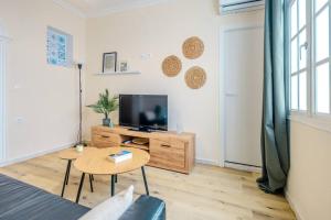 a living room with a tv and a table at Cadizz Entre Cielo y Mar Centro del Puerto ciudad in El Puerto de Santa María