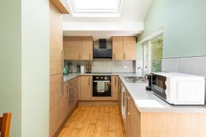 a kitchen with wooden cabinets and a white microwave at Spacious 3BR Home - Comfort & Convenience in Manchester