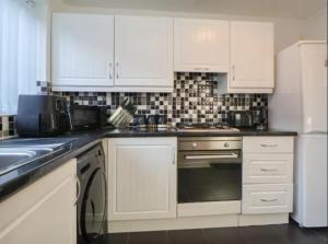 a kitchen with white cabinets and a white refrigerator at Anfield Stadium House - Free Parking in Liverpool +29 photos