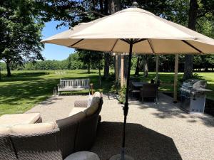 Cottage That Overlooks The Field的露台上配有烧烤架的大遮阳伞