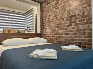 - une chambre avec un mur en briques et un lit avec des serviettes dans l'établissement Apartman Nani - Secure and free parking space!, à Sarajevo