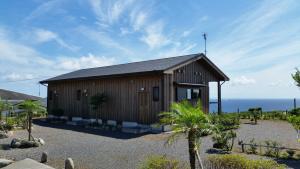 a small wooden building with the ocean in the background at Minnsyuku Yakushimaya in Yakushima