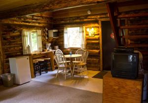 Una sala de estar con una mesa y sillas y un televisor. en Midnight Sun Log Cabins, en Moose Pass