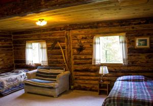 1 dormitorio con 1 cama y 1 silla en una cabaña de madera en Midnight Sun Log Cabins, en Moose Pass