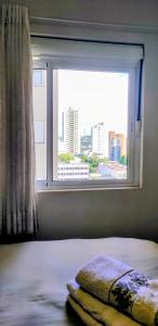 ein Schlafzimmer mit einem Fenster und einer Decke auf einem Bett in der Unterkunft AP Vista do Parque in Cascavel