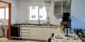 Eine Küche mit weißen Schränken, Spüle und Herd in der Unterkunft AP Vista do Parque in Cascavel + 10 Fotos