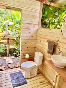 a wooden bathroom with a toilet and a sink at Casa Caimito in Nuquí