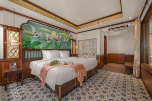 a bedroom with a large bed with a painting on the wall at Soleil by Soluna - A Charming Touch of Hoi An Heritage - formerly Hoi An Babylon Luxury Hotel in Hoi An