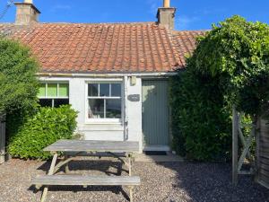 a wooden picnic table in front of a house at May Isle in Crail