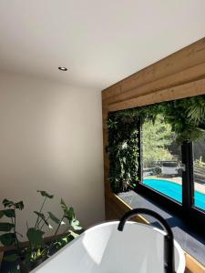 une salle de bain avec baignoire et fenêtre avec plantes dans l'établissement Alt'R & Go Exceptional house, à La Celle-sous-Gouzon