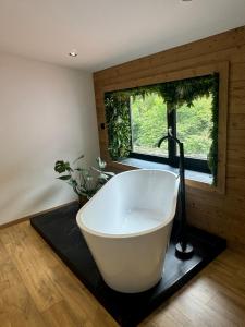 une baignoire dans une salle de bain avec une fenêtre dans l'établissement Alt'R & Go Exceptional house, à La Celle-sous-Gouzon