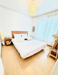 ein Schlafzimmer mit einem Bett mit weißen Laken und einem Fenster in der Unterkunft Joy Stay 상수역3분 한강3분 홍대5분 조용,깨끗한 감성 투룸 in Seoul